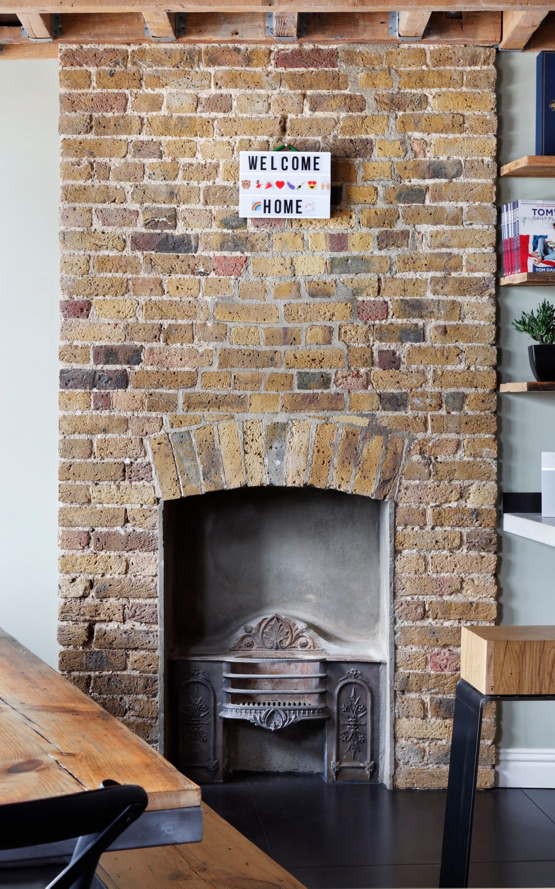 Industrial loft kitchen of Tom Daley with oak and steel THE LINE bar stool and fireplace in the background, showing modern warmth and character.