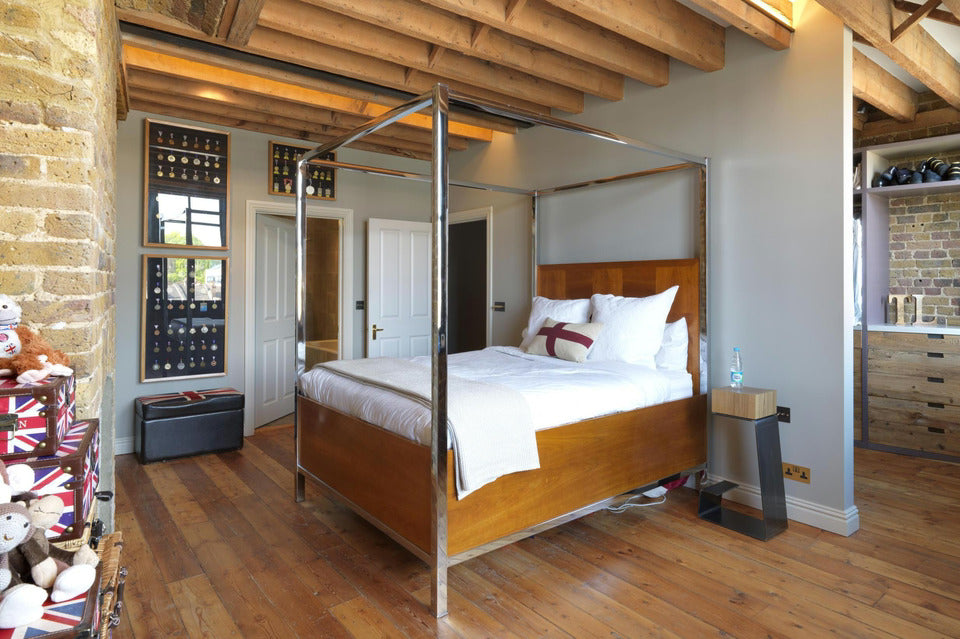 THE LINE bar stool used as a modern nightstand next to an elevated American-style bed in Tom Daley’s London loft bedroom.