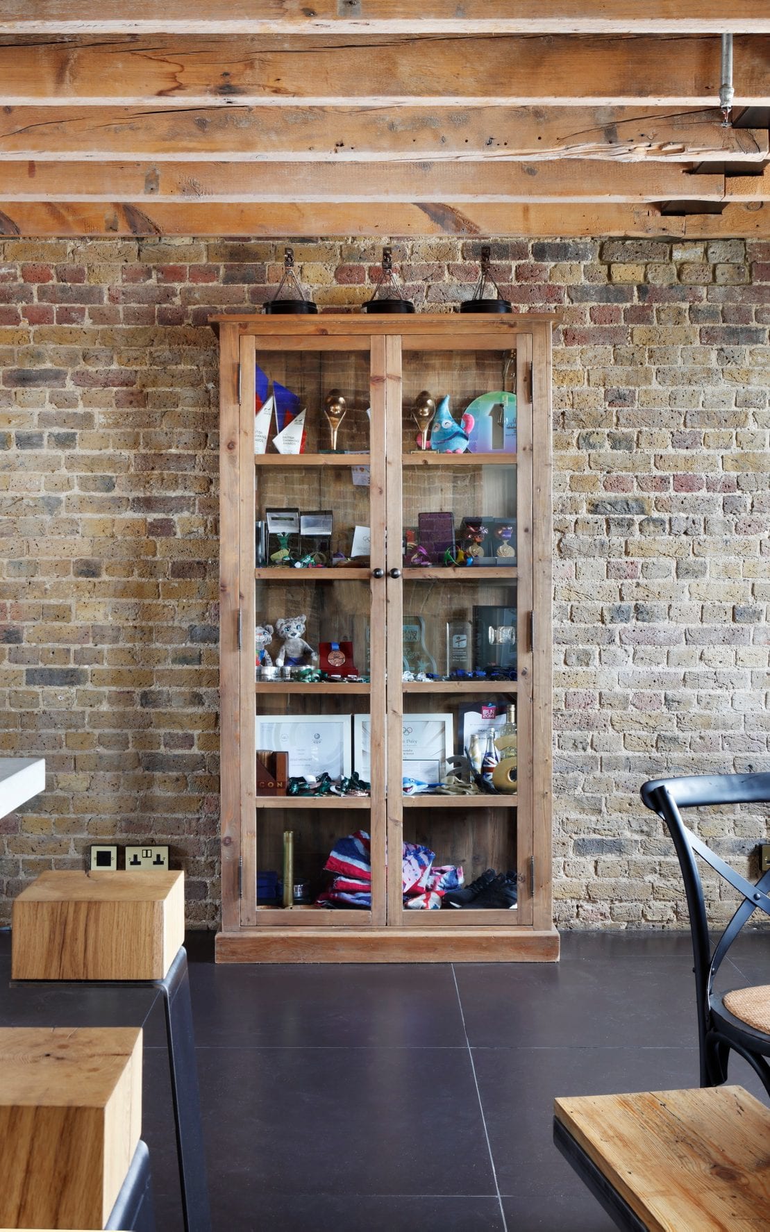 THE LINE bar stools in the kitchen of Tom Daley’s London loft, with a trophy display cabinet in the background, blending modern loft style with personal touches.