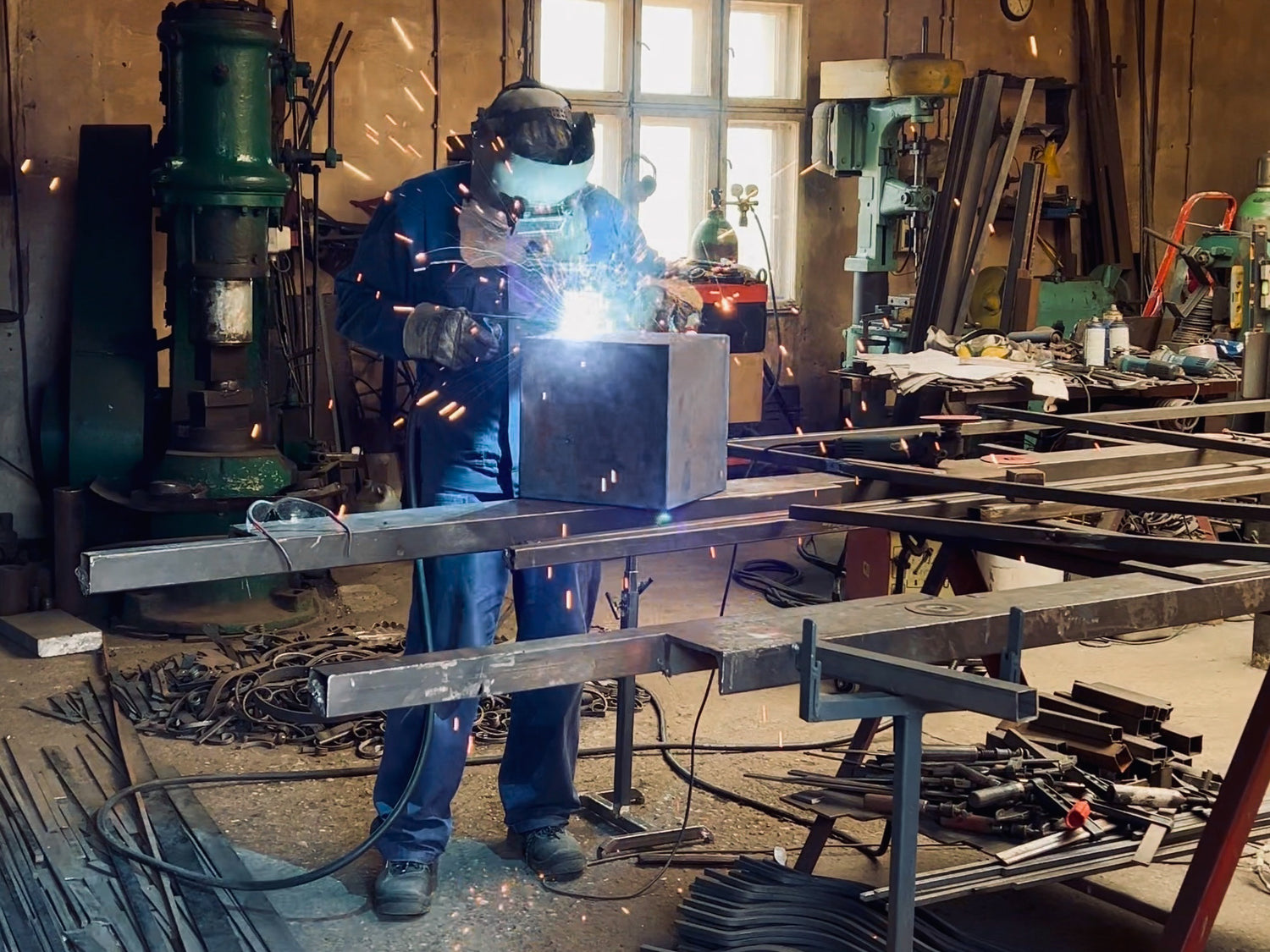 Artisan welder shaping THE BOX from raw steel in workshop, with welding sparks highlighting the intensity and craftsmanship of the process.