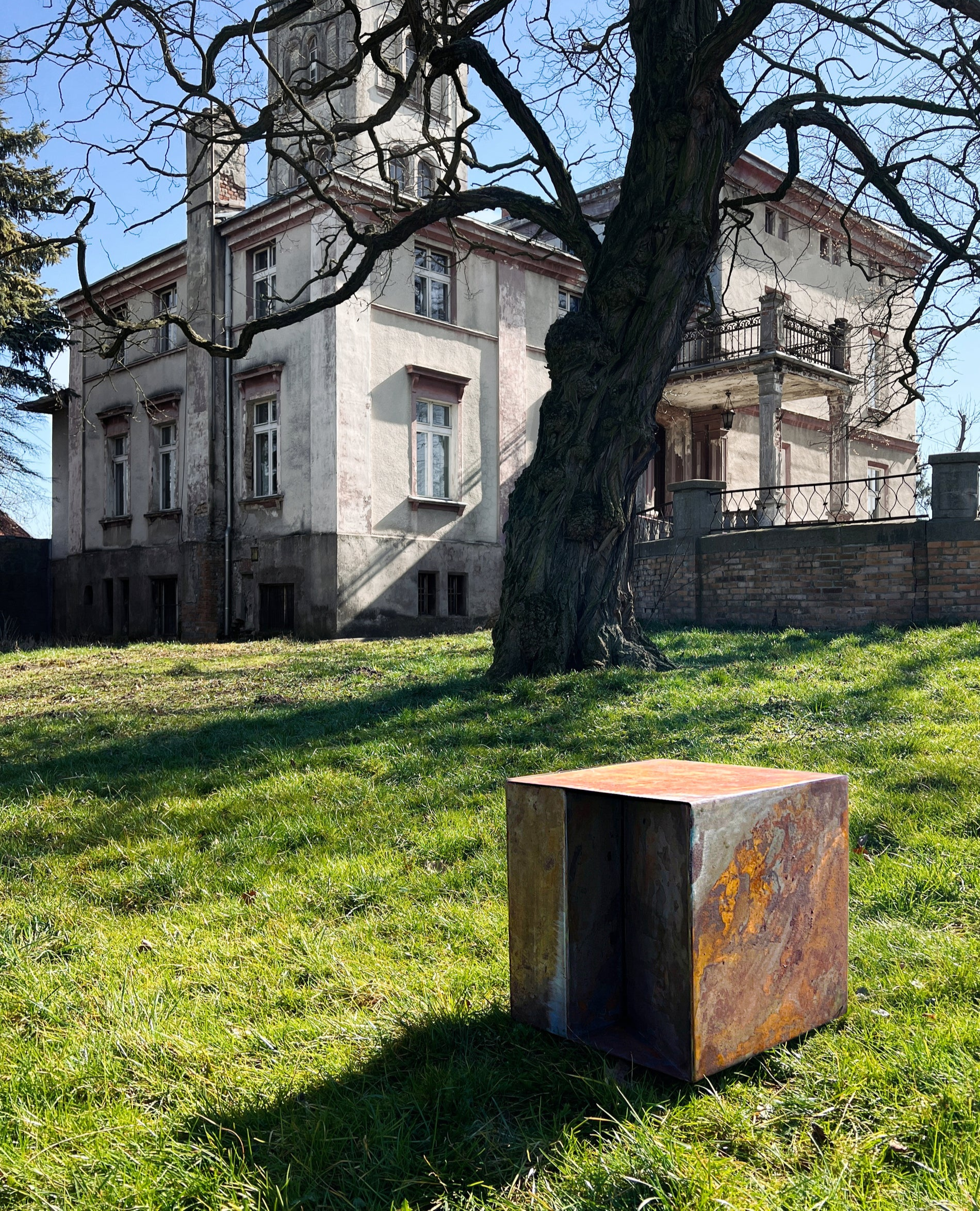 Sculptural THE BOX coffee table weathering in palace garden, exposed to nature as part of the rust development process.