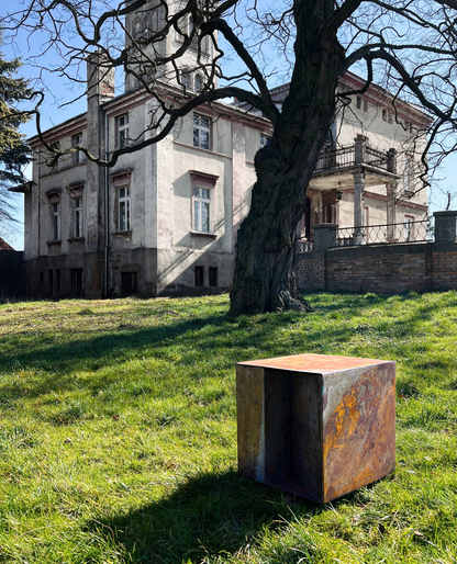 Sculptural THE BOX coffee table weathering in palace garden, exposed to nature as part of the rust development process.